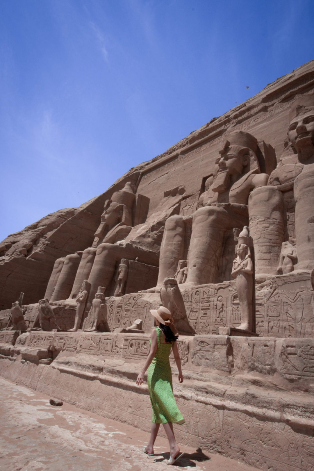 Travel Blogger Jordan Gassner walking alongside the exterior of the Great Temple of Abu Simbel, underneath the colossal statues of Pharaoh Ramses II