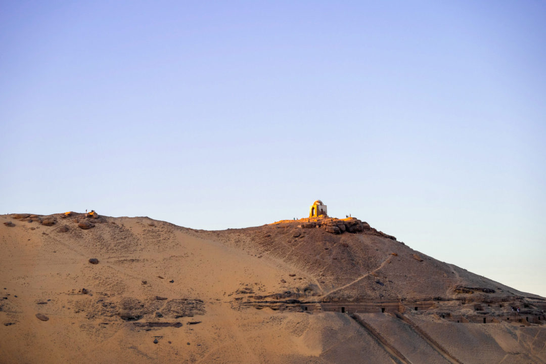 The lone dome of Qubbet El-Hawa, an ancient archaeological site along a hill in Aswan Egypt, sparkling in the sun