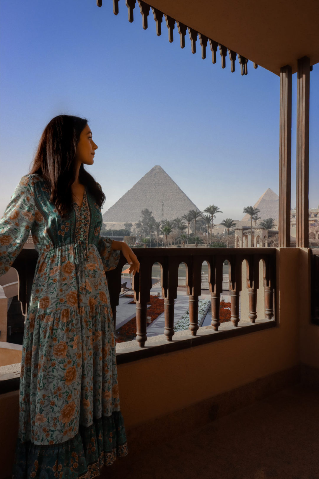 Travel Blogger Jordan Gassner leaning against a railing to look at the Pyramids of Giza from a stairway at Marriott Mena House in Egypt