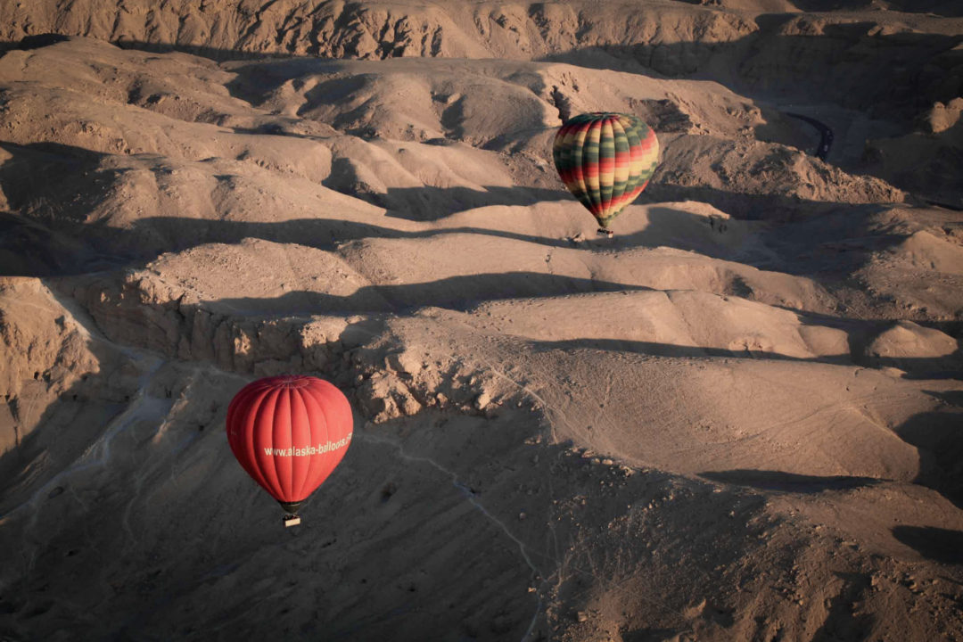 Two hot air balloons soaring over the Valley of the Kings in Luxor, Egypt