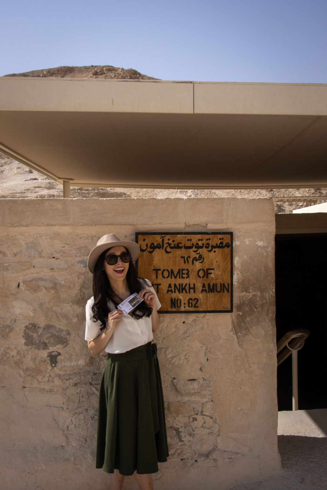 Travel Blogger Jordan Gassner holding her entry ticket with an excited expression in front of the Tomb of Tutankhamun in Luxor, Egypt
