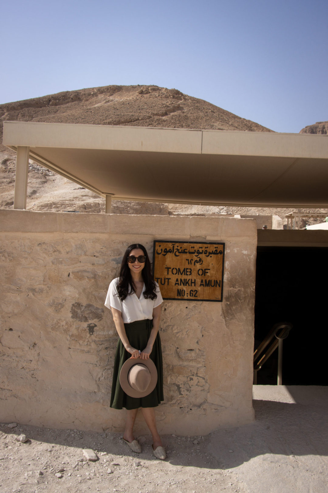 Travel Blogger Jordan Gassner standing and smiling while dressed in an Indiana Jones inspired outfit in front of the Tomb of Tutankhamun