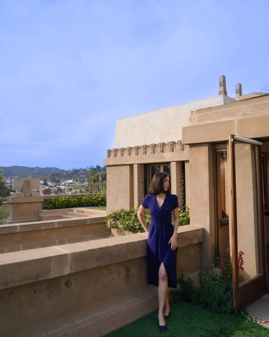Home Tours in Los Angeles: Travel Blogger Jordan Gassner looking inside a doorway from the backyard of Hollyhock House in Los Angeles