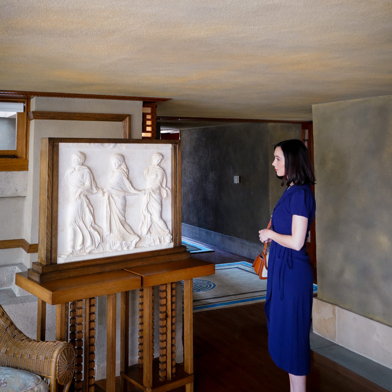 Travel Blogger Jordan Gassner looking at a sculpture with three figures inside Hollyhock House, the first Los Angeles UNESCO World Heritage Site