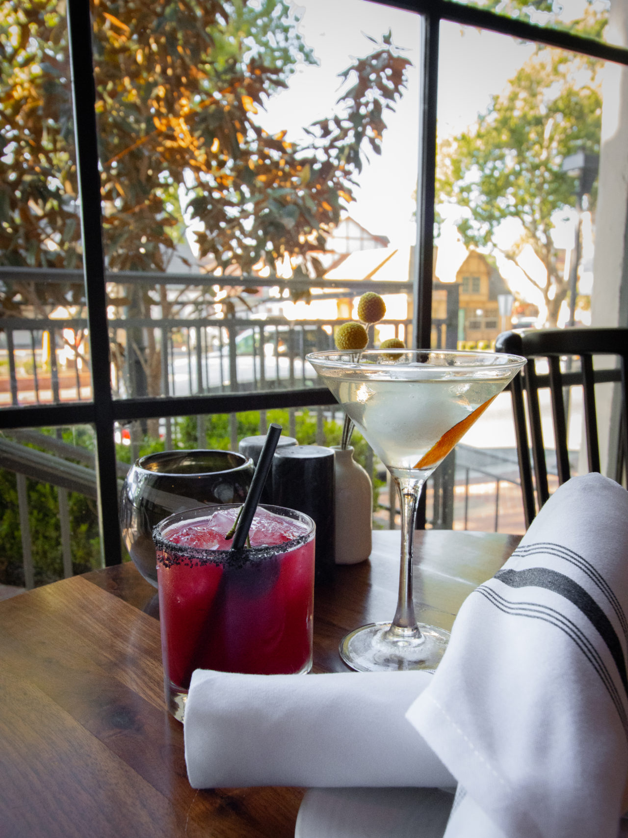 Solvang Travel Guide: Two cocktails on a table near a window at the Mad & Vin restaurant in the Landsby Hotel in Solvang, California