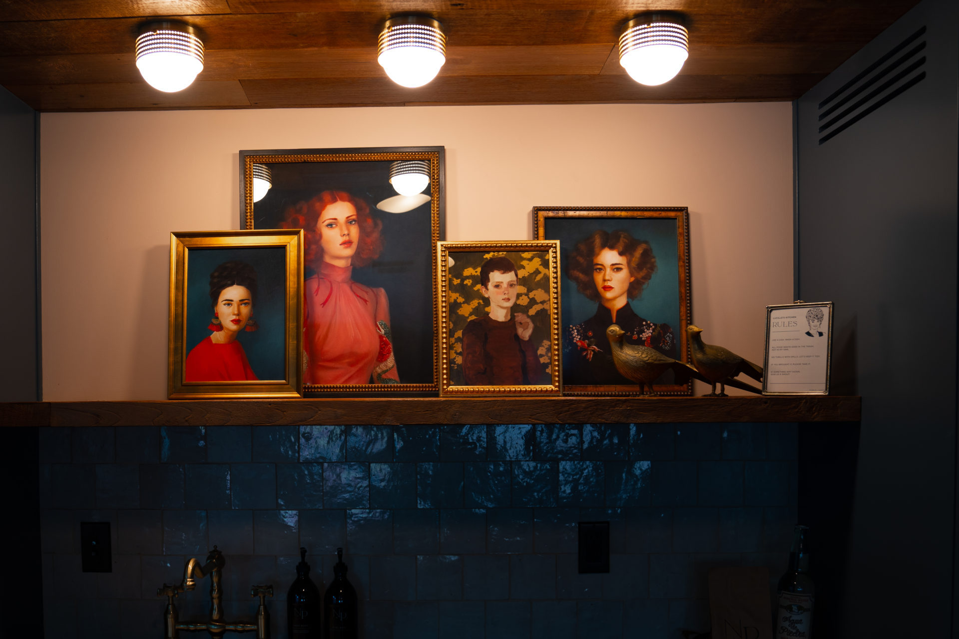 Four portraits of women with big hair above the kitchen sink in Lucille's Manor at the Noble and Proper Hotel in Big Bear, California