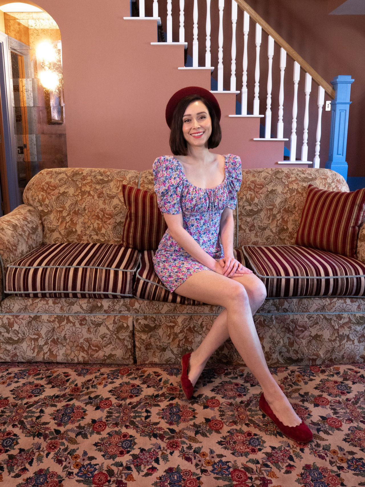 Travel Blogger Jordan Gassner sitting and smiling on the red and brown sofa inside Fran's Flat at the Noble + Proper Hotel in Big Bear, California