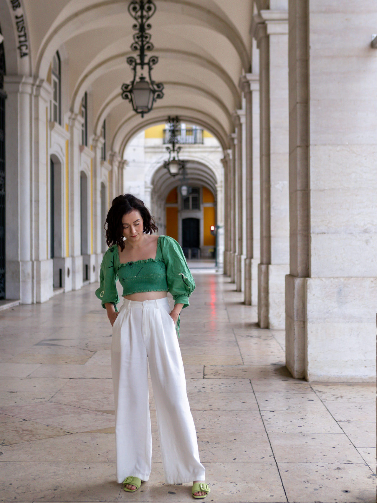 Travel Blogger Jordan Gassner looking down at her shoes while standing underneath the Arco da Rua Augusta in Lisbon
