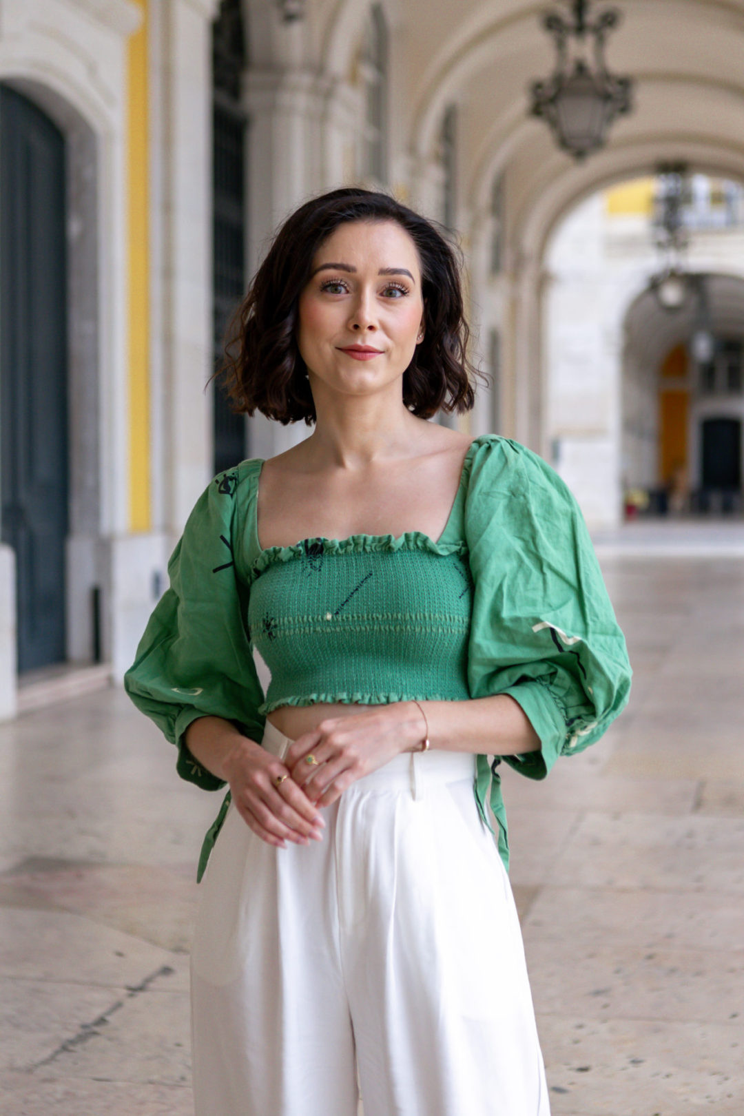 A portrait shot of Jordan Gassner looking at camera underneath the Arco da Rua Augusta, one of her favorite spots for photos in Lisbon