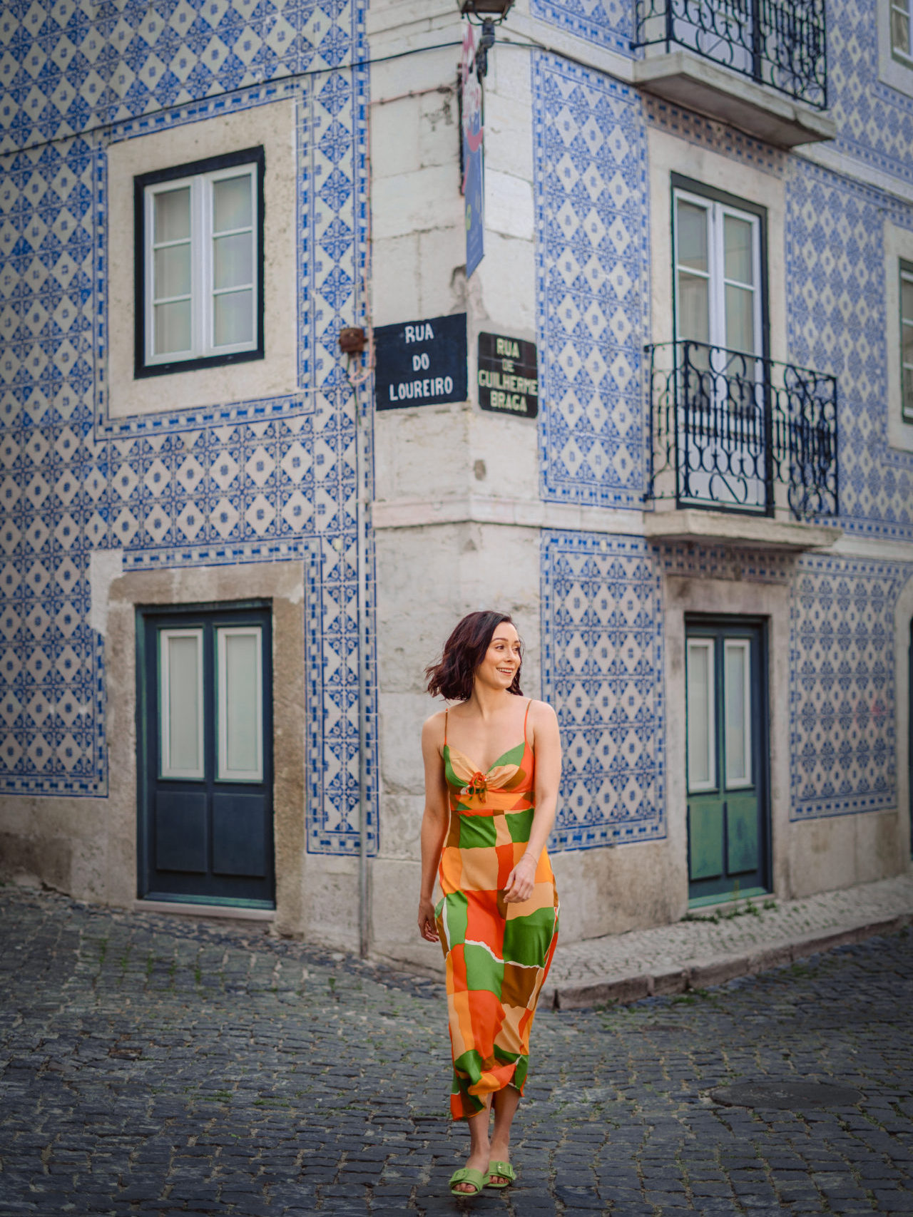 Travel Blogger Jordan Gassner walking in front of a blue tiled building in Alfama, an older neighborhood in Lisbon