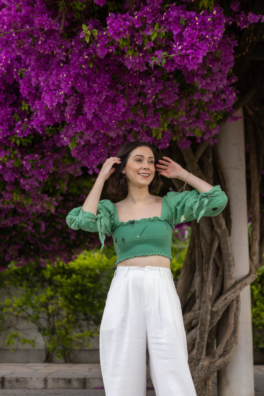 Travel Blogger Jordan Gassner wearing Capulet, Nonchalant the Label and a gold bracelet in front of a Bougainvillea tree in Lisbon, Portugal