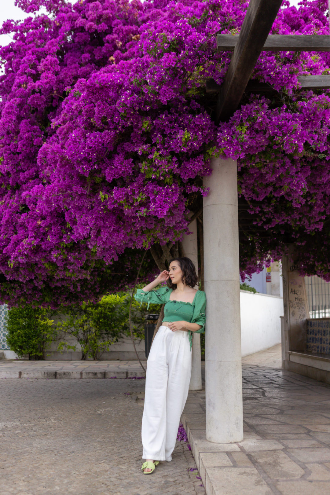 Travel Blogger Jordan Gassner leaning against a post in front of a Bougainvillea tree in Lisbon, Portugal