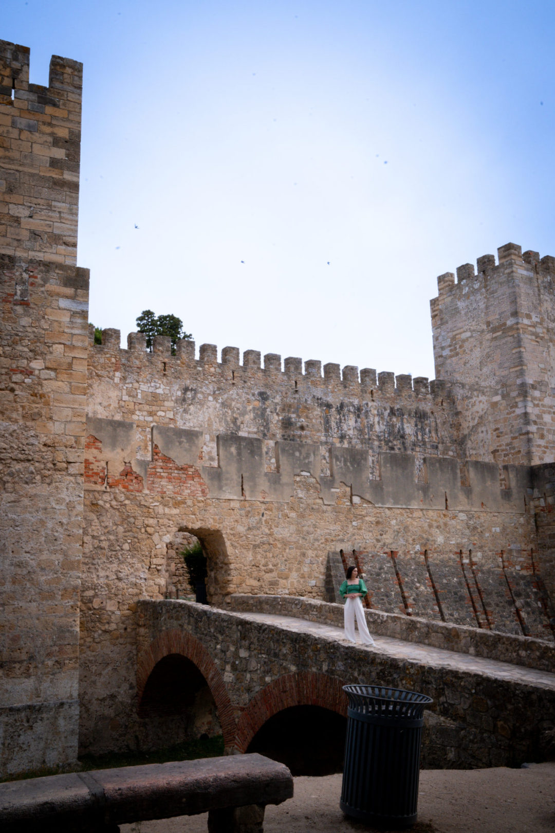 Travel Blogger Jordan Gassner standing along the bridge leading up to the entrance of Castelo de São Jorge in Lisbon, Portugal