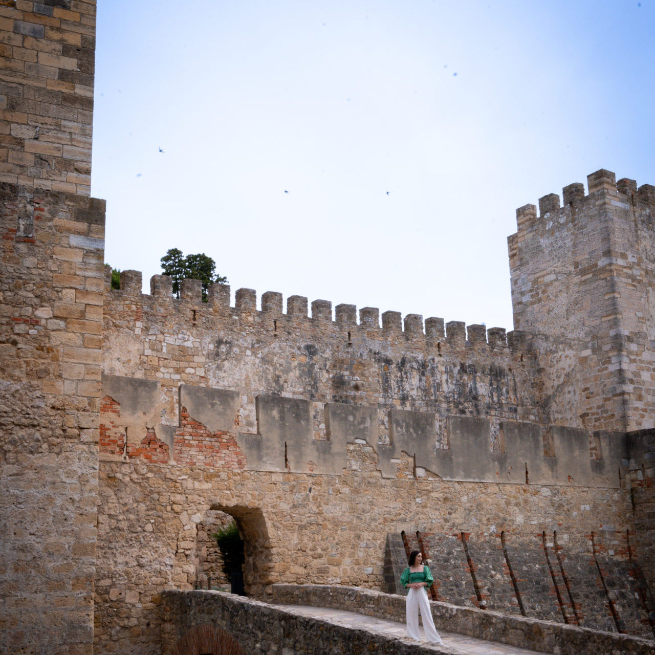 Travel Blogger Jordan Gassner standing along the bridge at the entrance of Sao Jorge Castle in Lisbon, Portugal