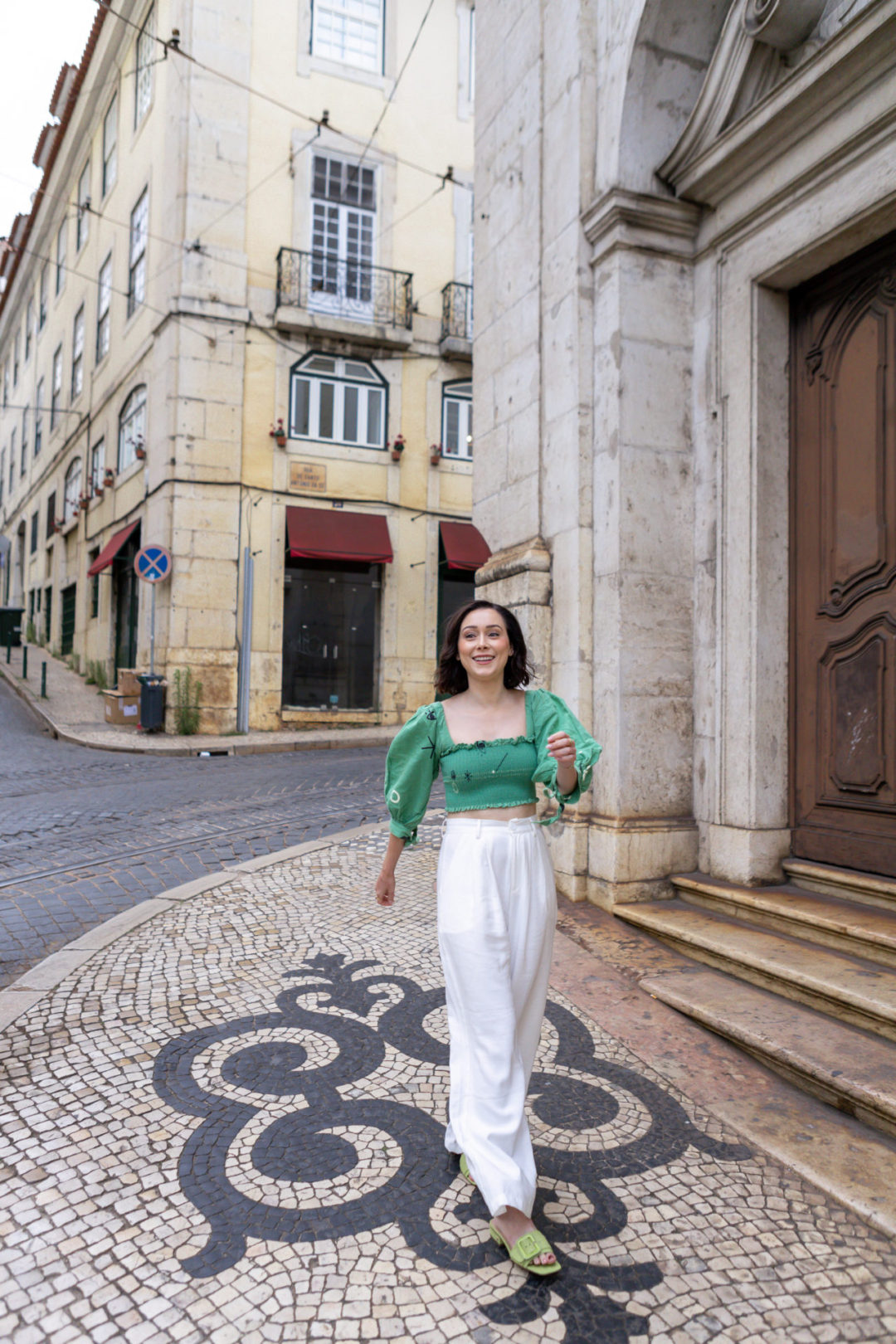 Travel Blogger Jordan Gassner laughing while walking by a historic church in Lisbon's Alfama neighborhood