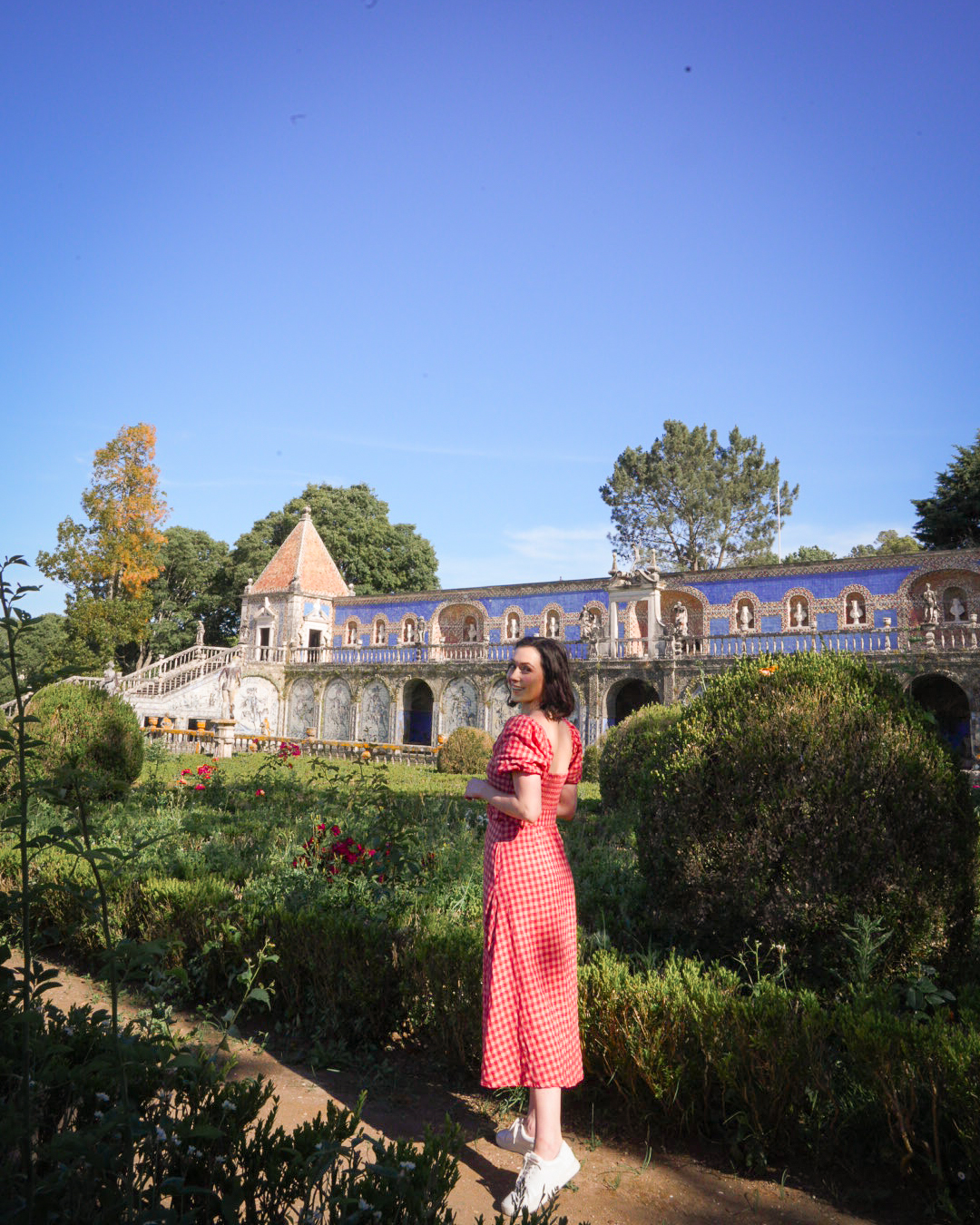 Travel Blogger Jordan Gassner looking over her shoulder and smiling along a pathway in the Palace Fronteira Gardens in Lisbon, Portugal