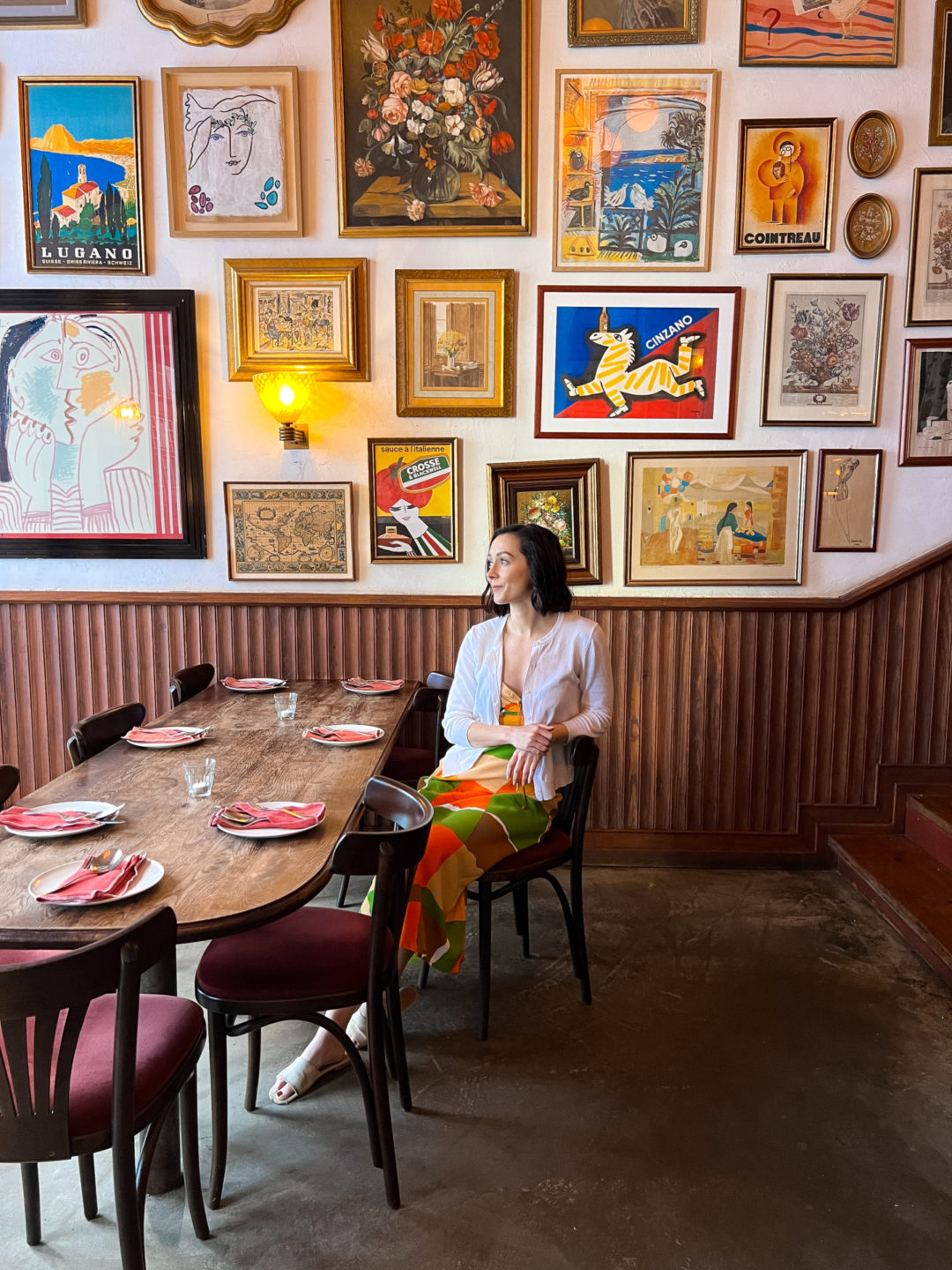 Travel Blogger Jordan Gassner sitting at a front table in front of a gallery wall of art inside Leonetta, an Italian restaurant in Lisbon, Portugal