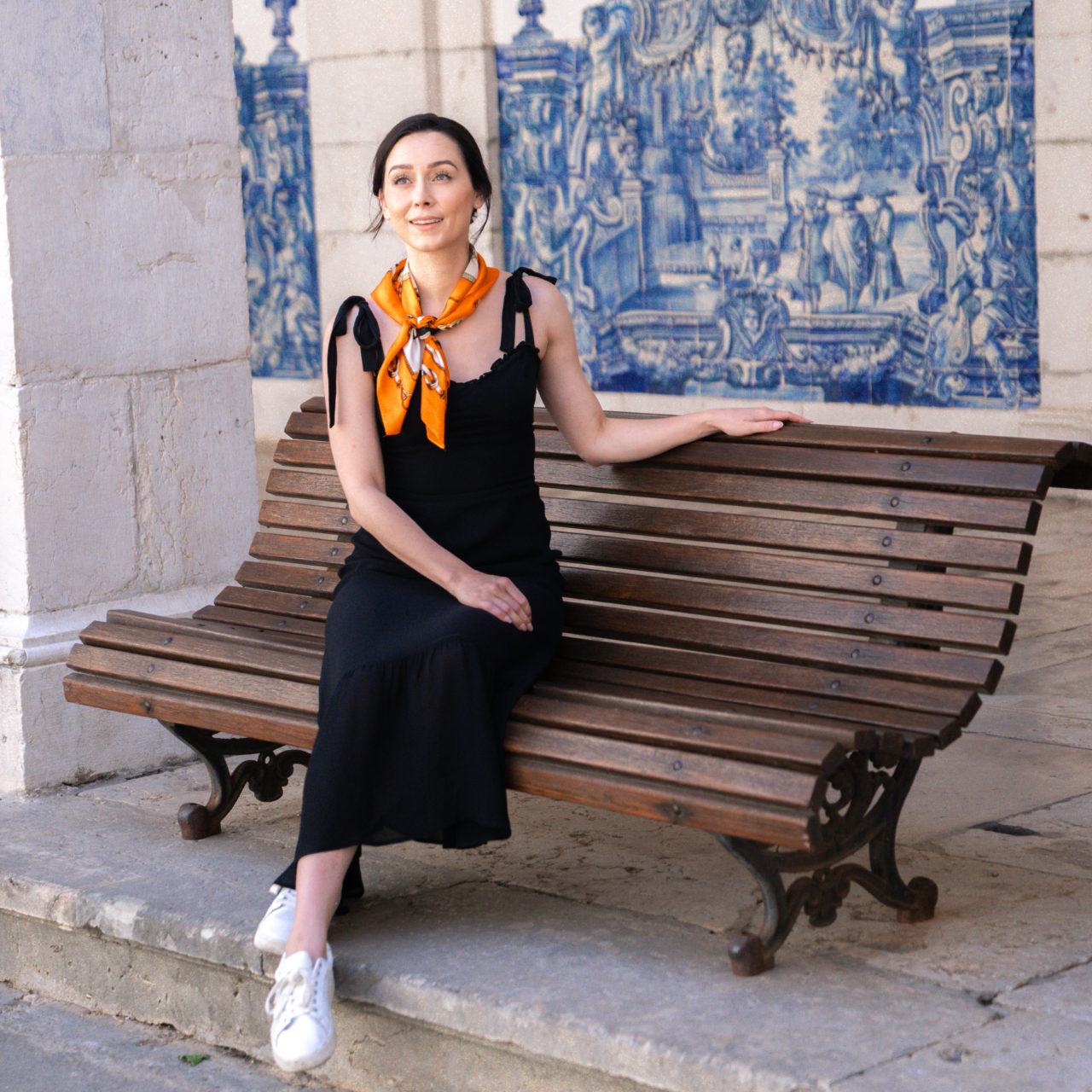 Travel Blogger Jordan Gassner sitting on a wooden bench in a couryard full of azulejo tiles in Mosteiro São Vicente De Fora in Lisbon, Portugal