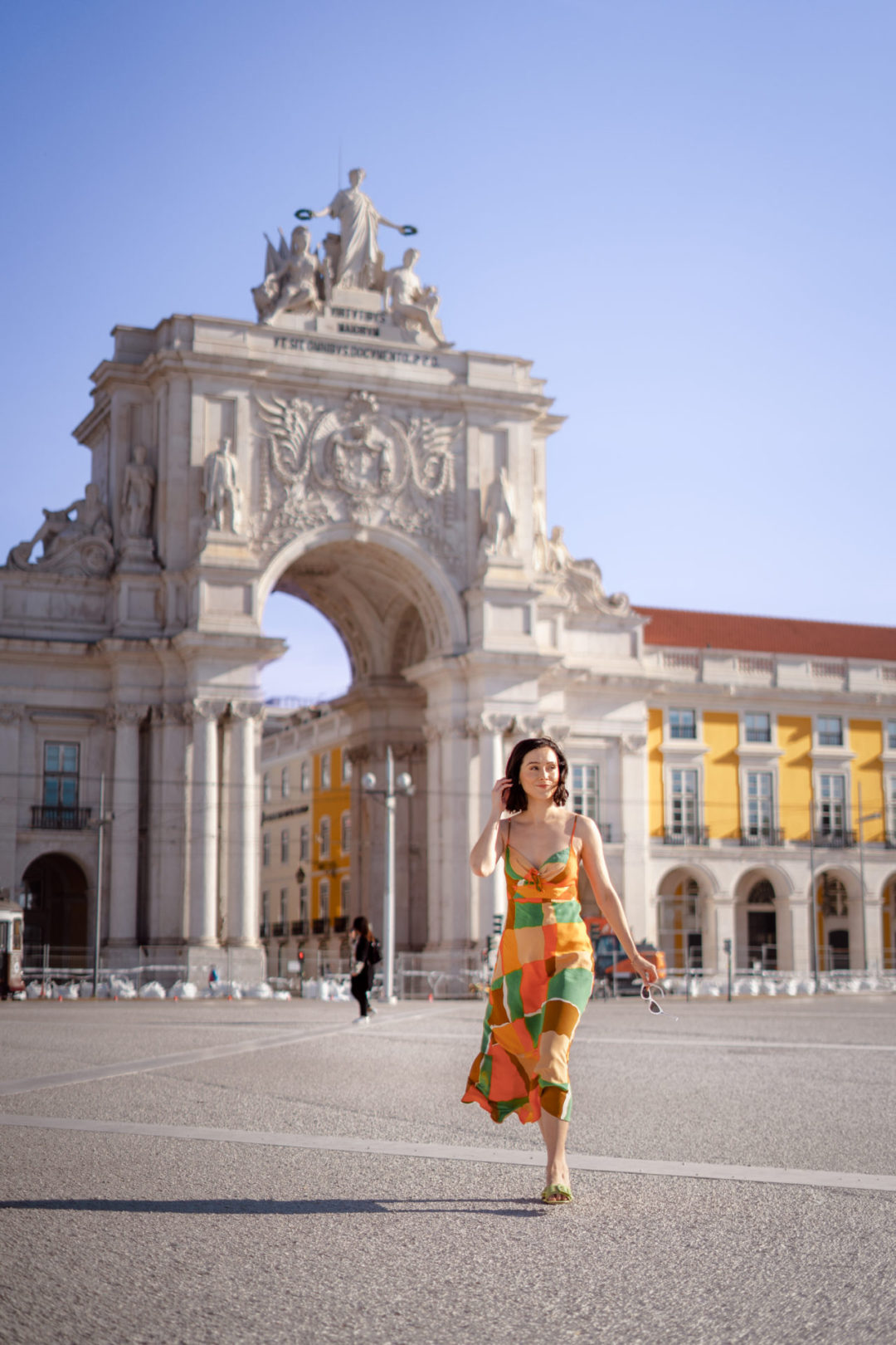 Travel Blogger Jordan Gassner holding a pair of sunglasses while walking through an empty Praça do Comércio in Lisbon, Portugal