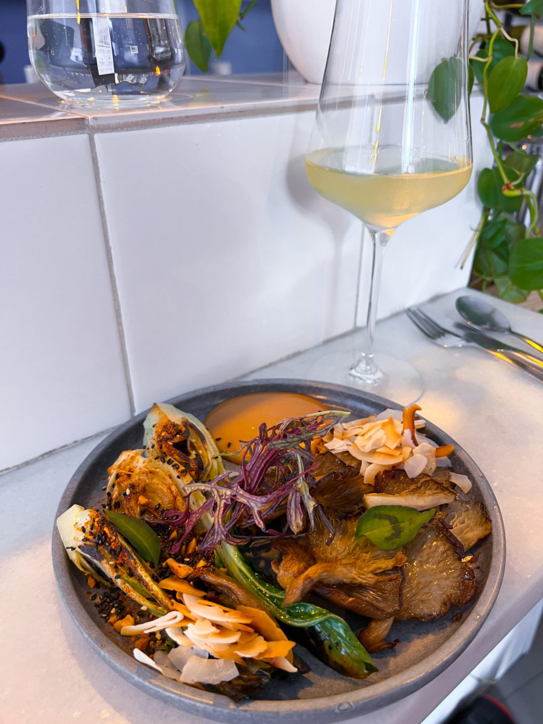 The Oyster Mushroom, Bok Choy, Soy, Peanut and Coconut dish and a glass of white wine from Senhor Uva in Lisbon, Portugal