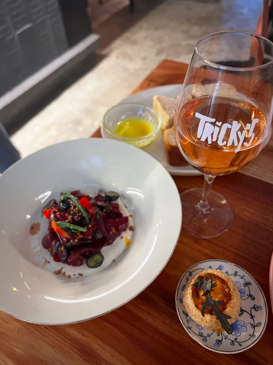 A glass of orange wine and two tapas dishes from Tricky's in Lisbon, Portugal