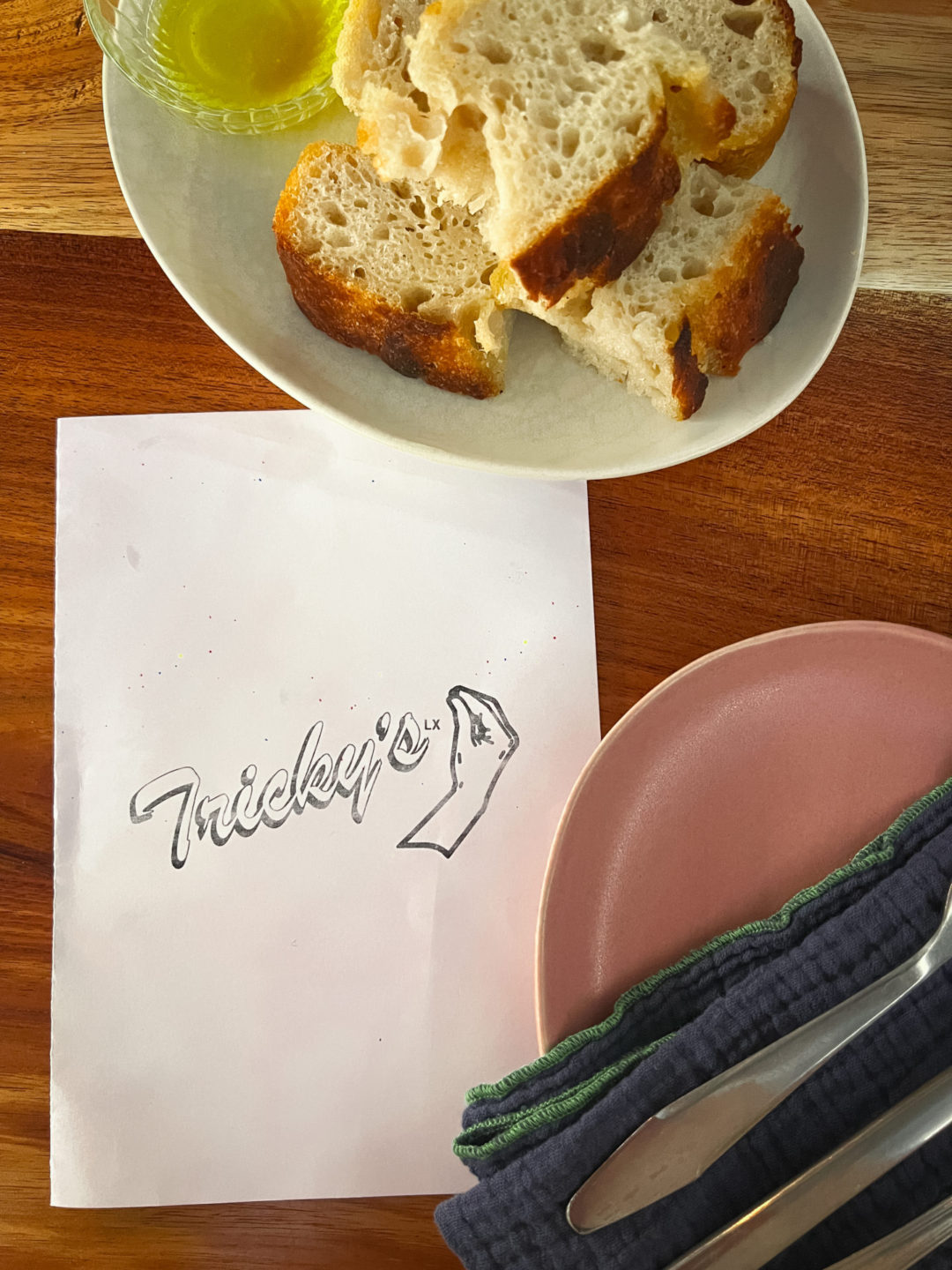 A plate of focaccia and olive oil by a menu at Tricky's in Lisbon, Portugal