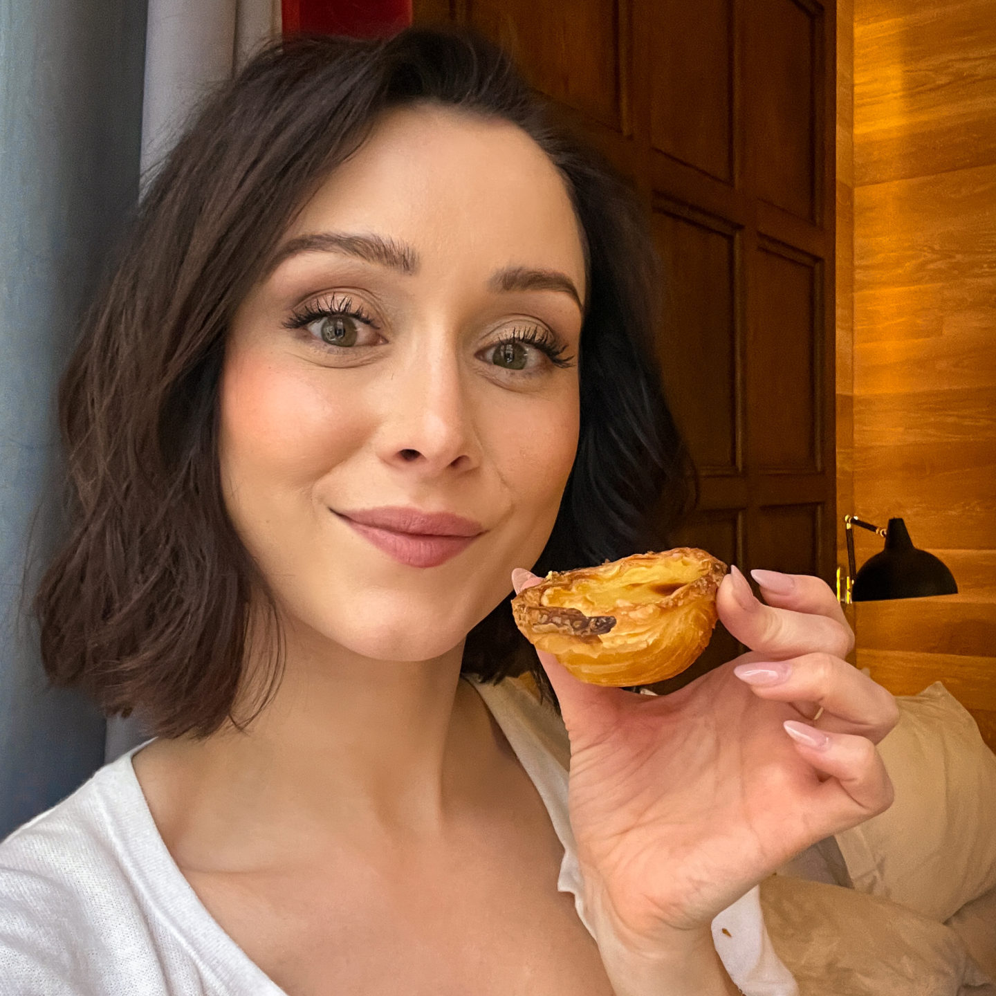 Travel Blogger Jordan Gassner smiling and holding a pastel de nata from Vegan Nata in Lisbon, Portugal