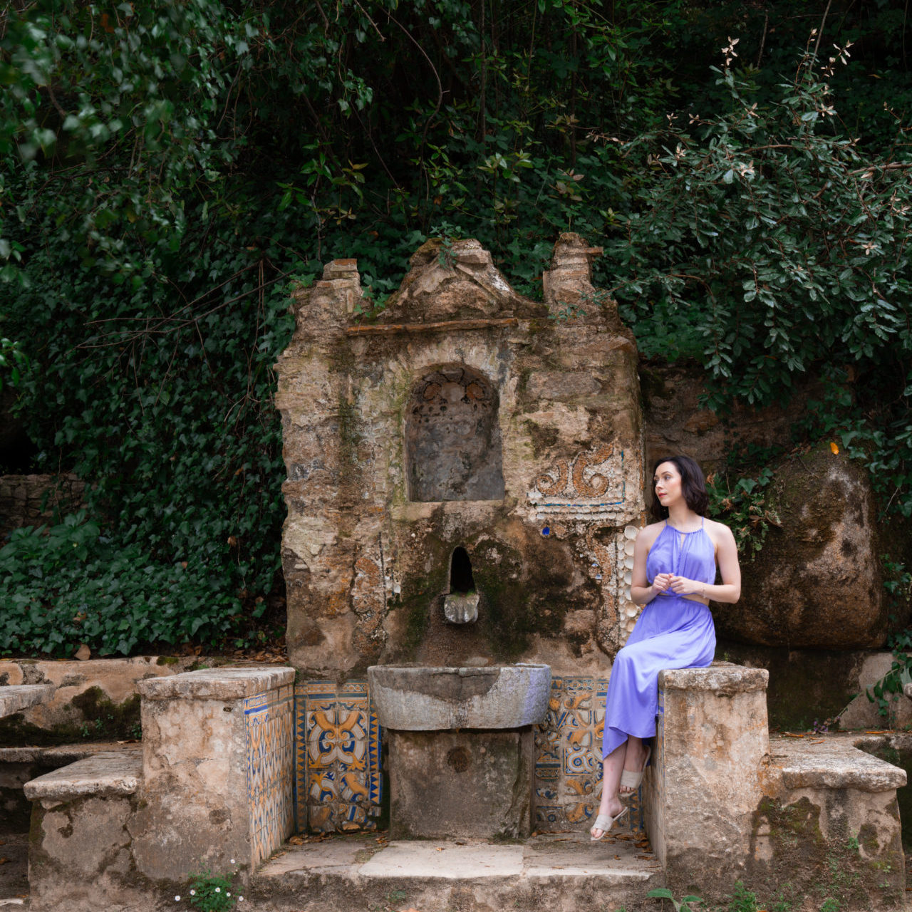 Travel Blogger Jordan Gassner sitting on a well in front of Convento dos Capuchos in Sintra, Portugal
