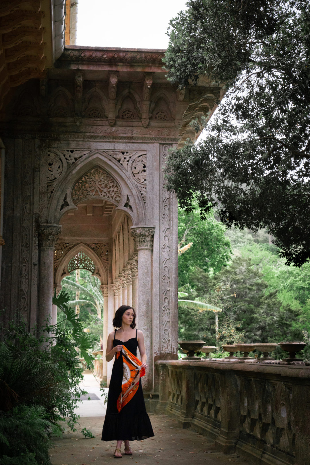Travel Blogger Jordan Gassner walking through Monserrate Palace in Sintra Portugal while wearing a Reformation dress and holding an orange scarf