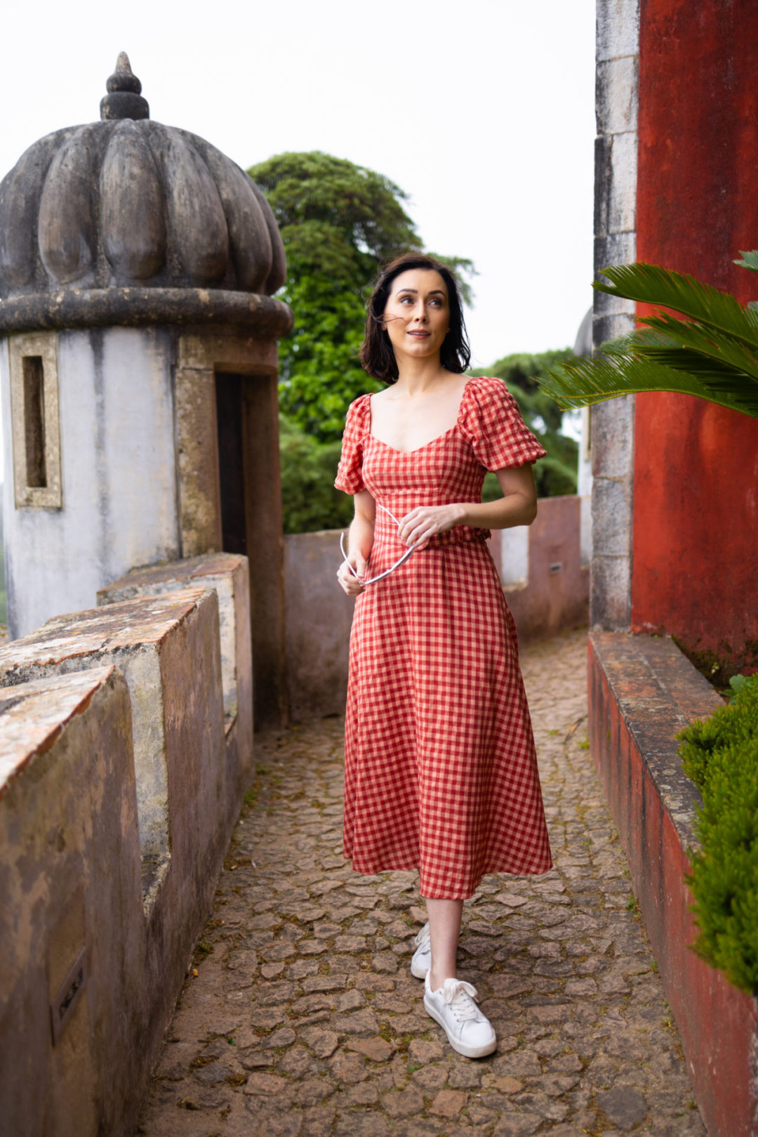 Travel Blogger Jordan Gassner holding a pair of white retro sunglasses at Pena Palace in Sintra, Portugal