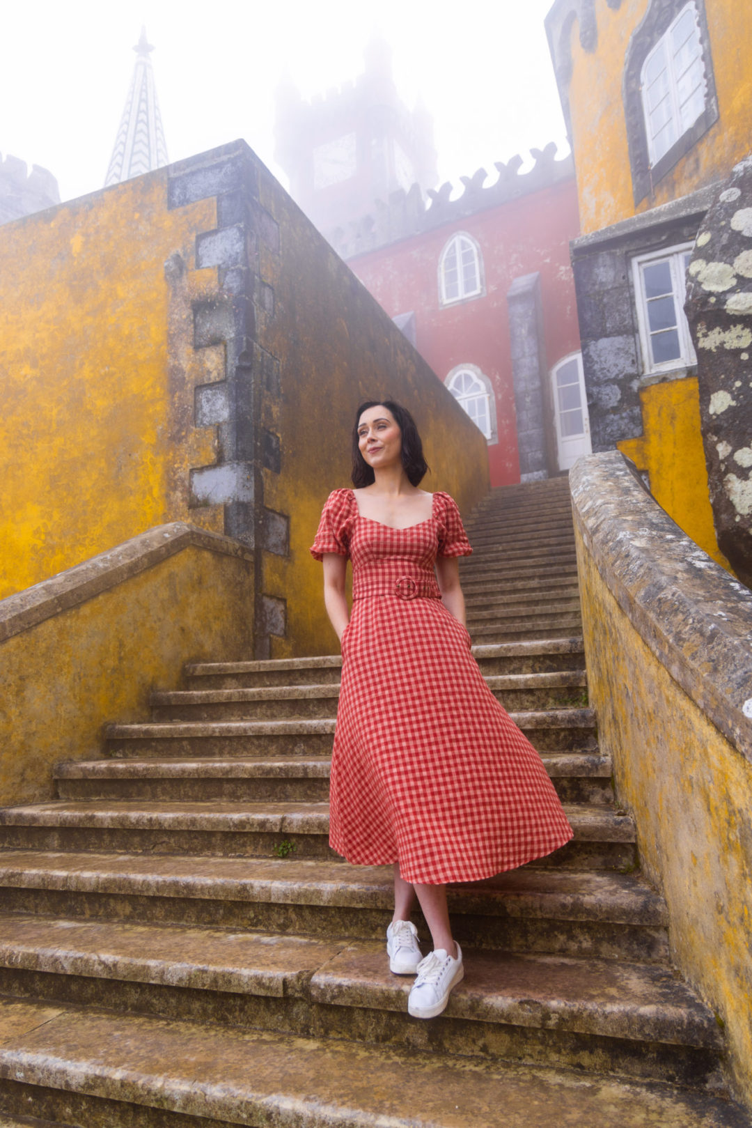 A Low angle photo of Travel Blogger Jordan Gassner standing on a staircase wearing a MinkPink Dress at Pena Palace in Sintra, Portugal