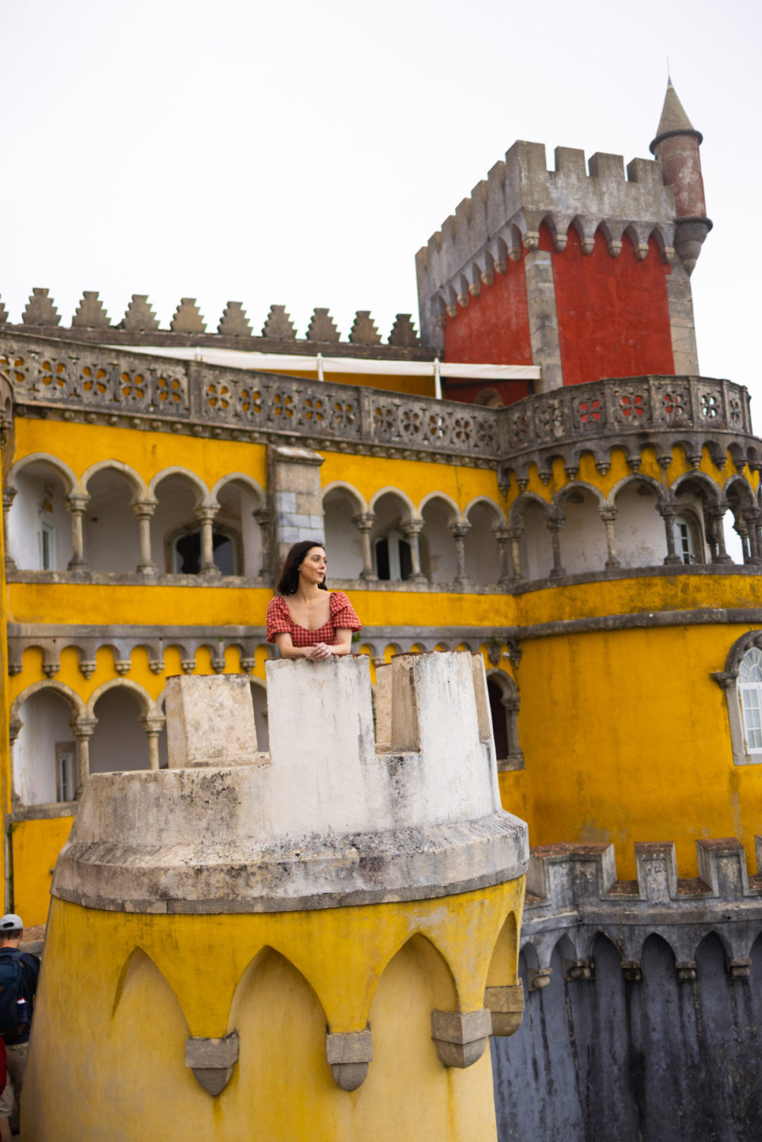 Travel Blogger Jordan Gassner looking out from a tower at the red and yellow Pena Palace in Sintra, Portugal