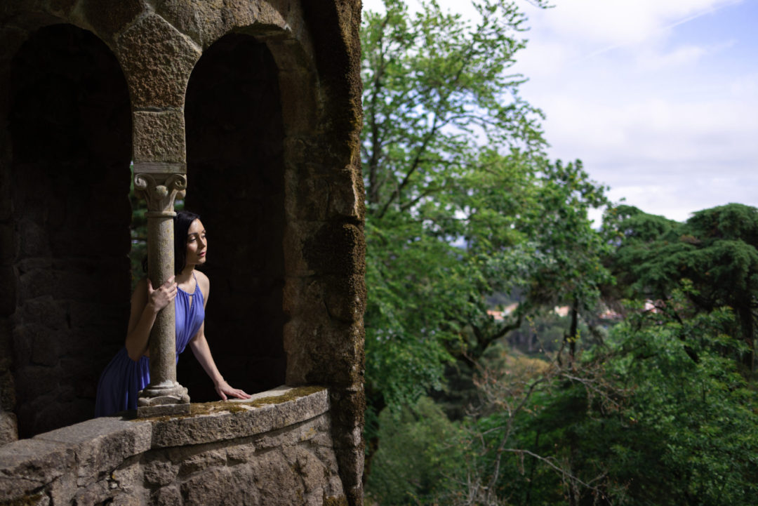 Travel Blogger Jordan Gassner wearing a Game of Thrones inspired outfit while peering out from a fantasy-designed tower at Quinta da Regaleira in Sintra, Portugal