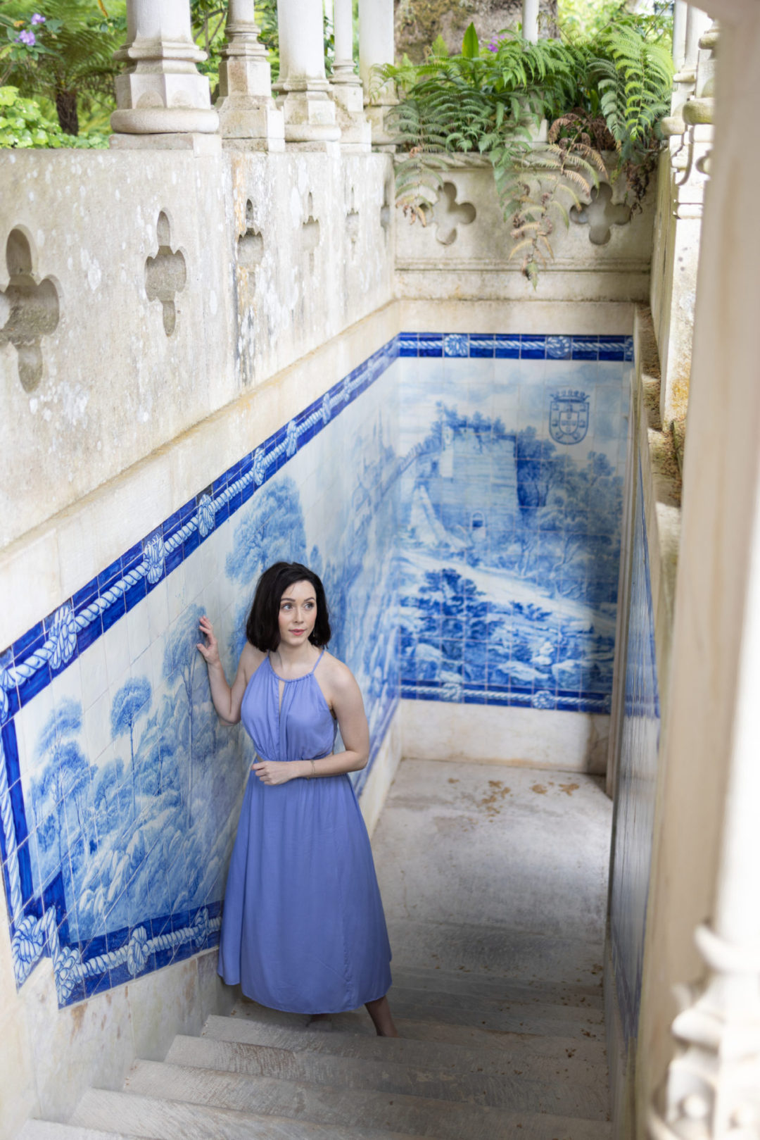 Travel Blogger Jordan Gassner walking up stairs surrounded by azulejo tiles in the gardens of Quinta Da Regaleira