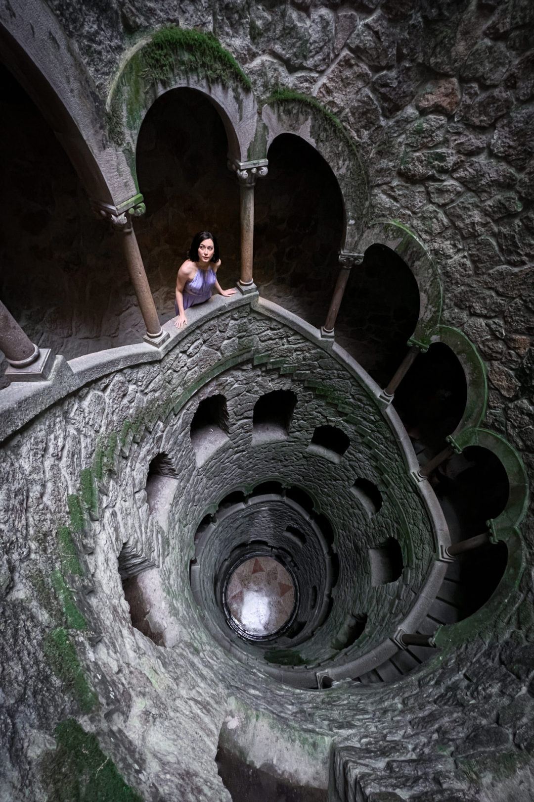 Travel Blogger Jordan Gassner looking up toward the light while climbing an empty Initiation Well at Quinta Da Regaleira in Sintra, Portugal