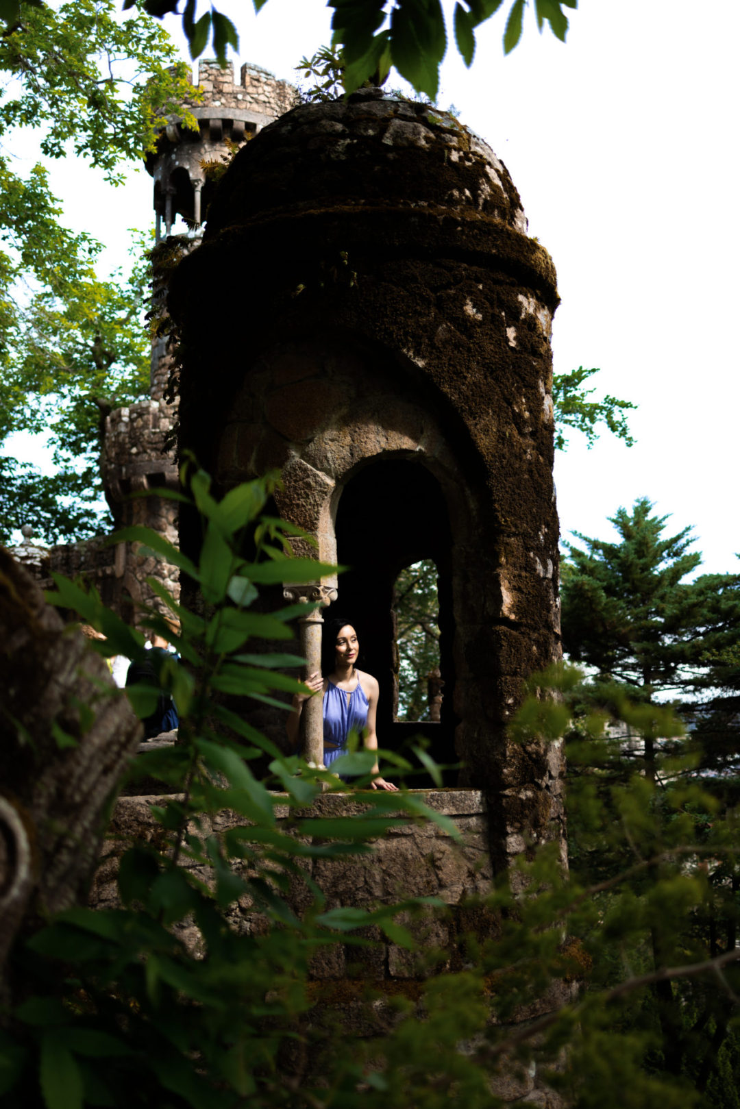 Travel Blogger Jordan Gassner peering out from a tower in the gardens of Quinta Da Regaleira