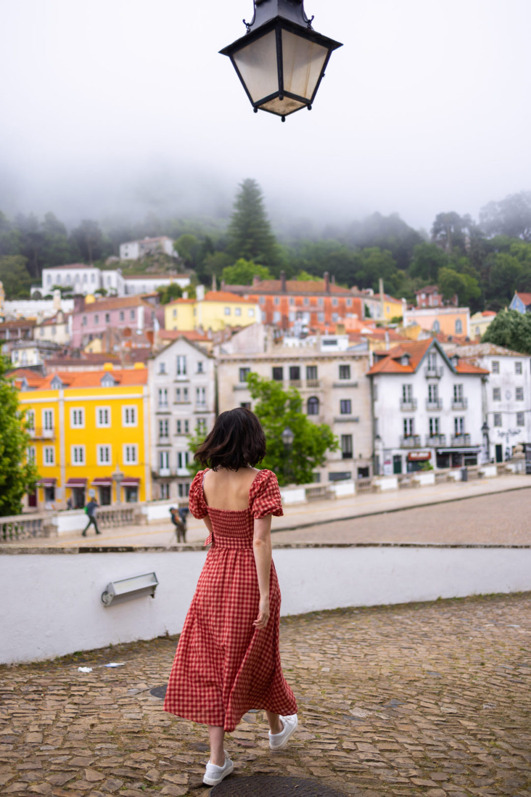 Travel Blogger Jordan Gassner walking toward the bright and pastel colored buildings of Sintra, Portugal's old town on a misty morning