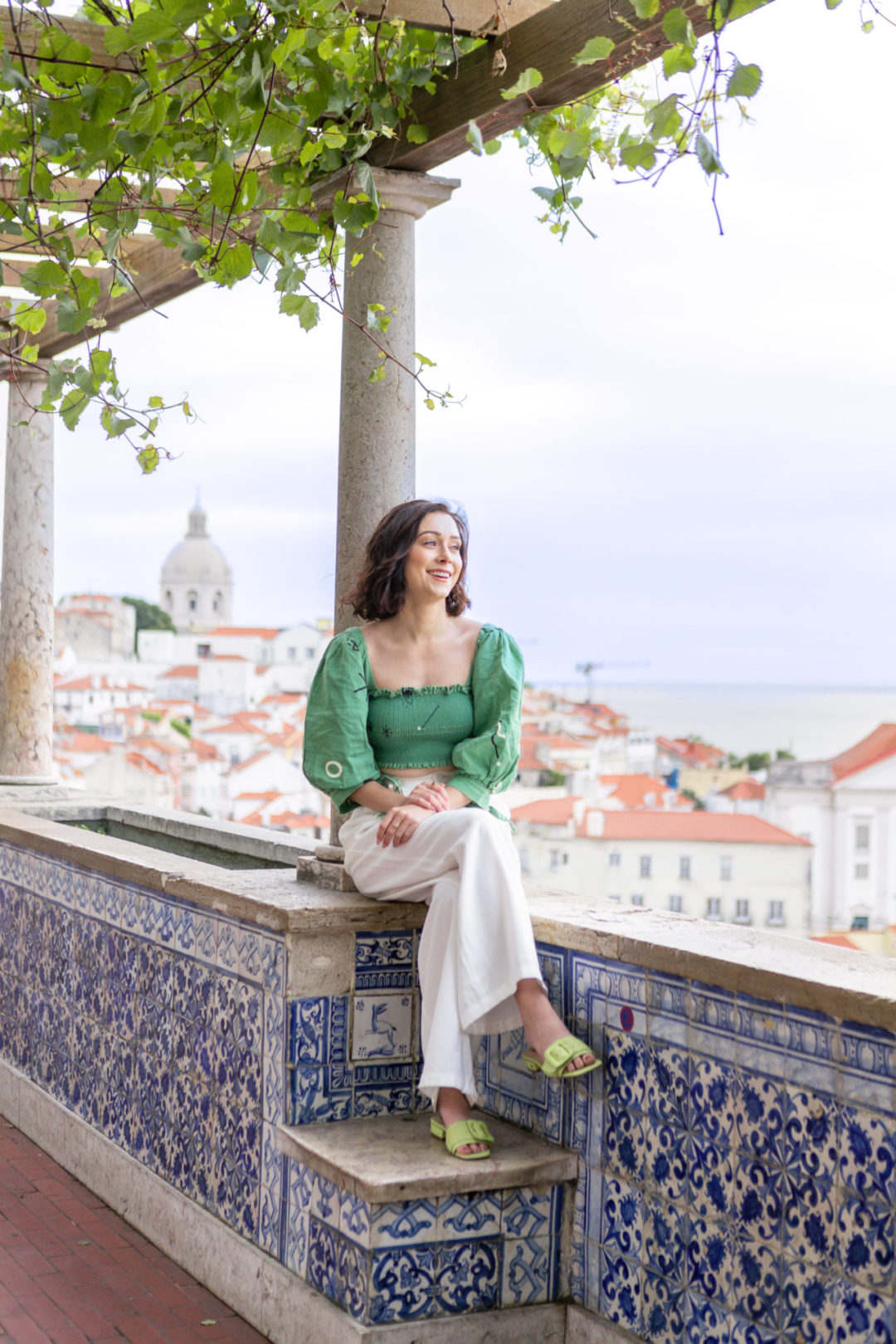 Lisbon Travel Guide: Travel Blogger Jordan Gassner sitting and laughing on top of Miradouro de Santa Luzia in Lisbon, Portugal
