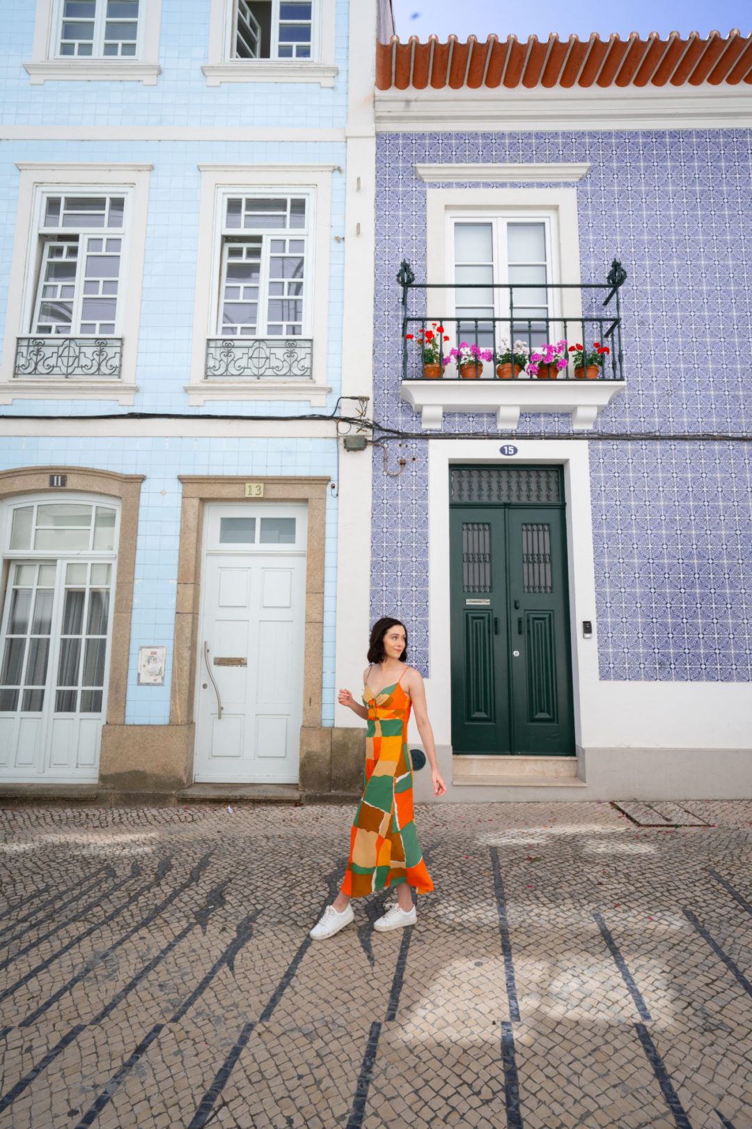 Travel Blogger Jordan Gassner walking in front of a set of two blue azulejo decorated buildings in Aveiro, Portugal