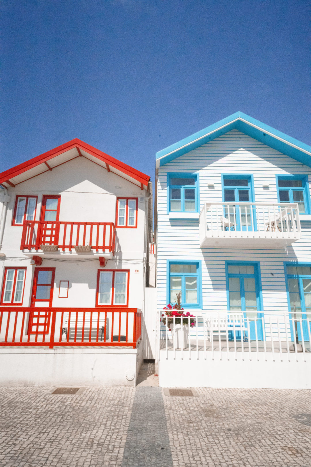 A red and white beach home next to a blue and white house in the beach town of Costa Nova, Portugal