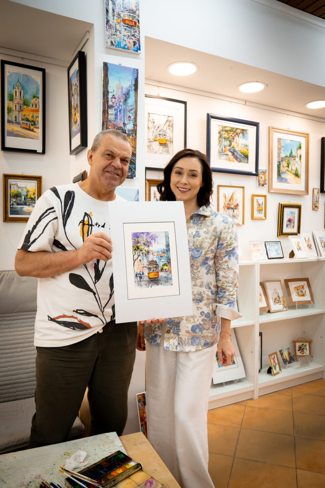 Travel Blogger Jordan Gassner standing and smiling next to a local watercolor artist inside his art gallery in Lisbon, Portugal
