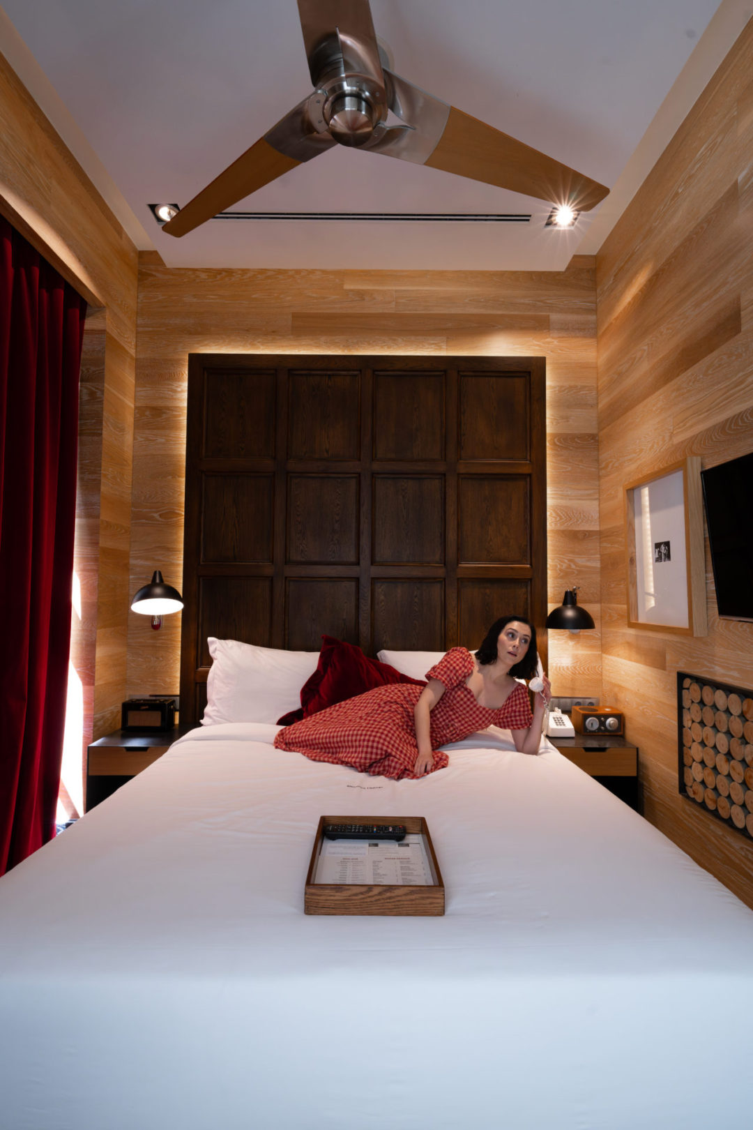 Travel Blogger Jordan Gassner holding up a phone while lounging on the bed inside a guest room in Brown's Central Hotel in Lisbon