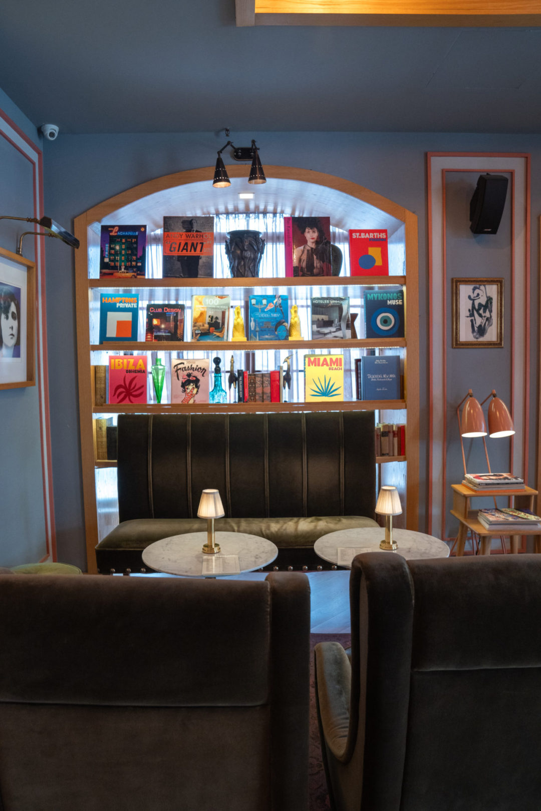 An inlaid bookcase with full of colorful coffeetable books against a blue wall inside Browns Central Hotel in Lisbon, Portugal