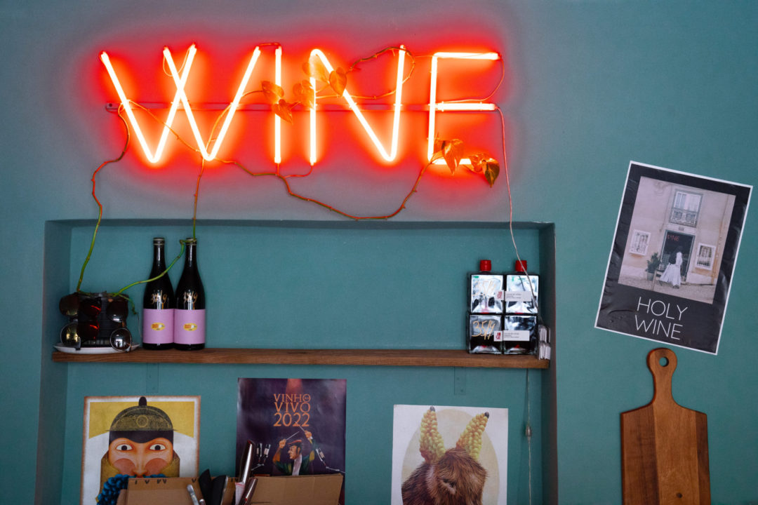 A red neon sign labeled "Wine" inside Holy Wine!, one of the best spots for Natural Wine in Lisbon