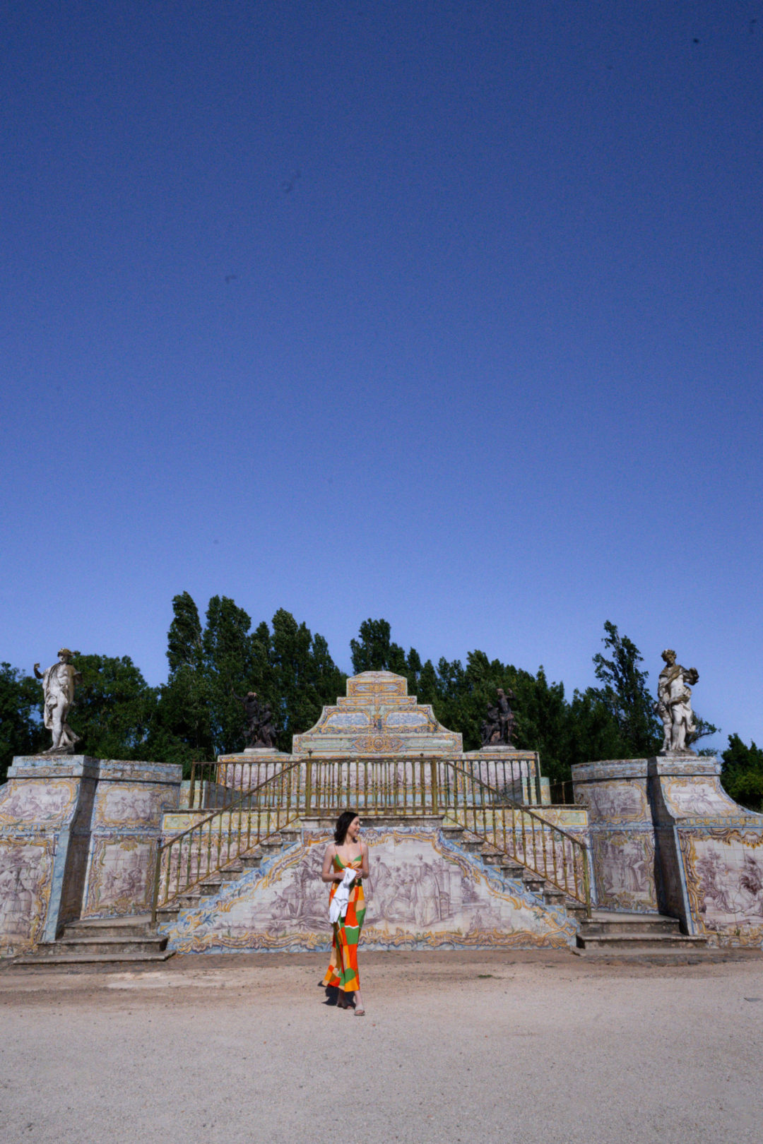 Travel Blogger Jordan Gassner looking right while standing in front of a staircase leading to a pool outside of Queluz Palace in Lisbon, Portugal