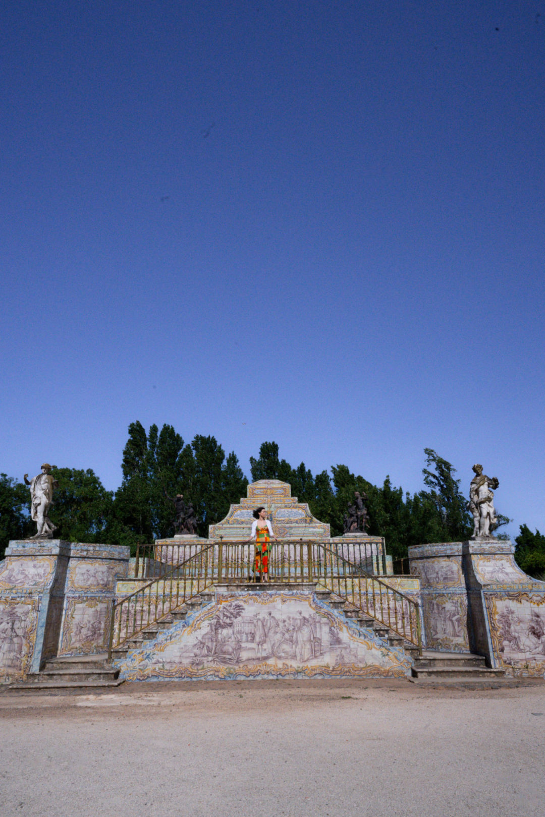 Travel Blogger Jordan Gassner looking out from the top of a staircase with sculptures and azulejos outside of Queluz Palace in Lisbon