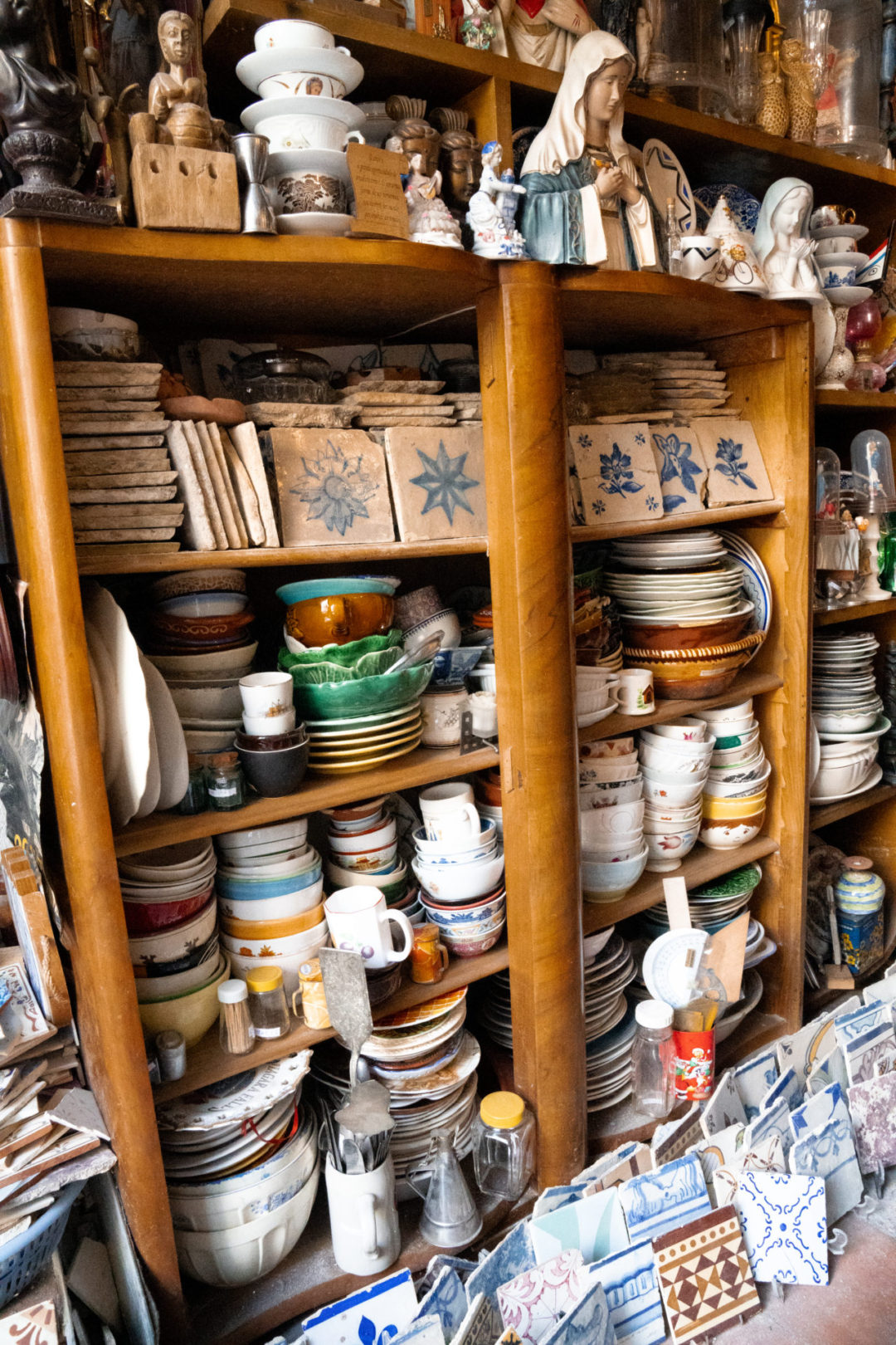 A series of shelves packed to the brim with old tiles, plates and other antiques inside Authentica Antiguidades in Lisbon, Portugal