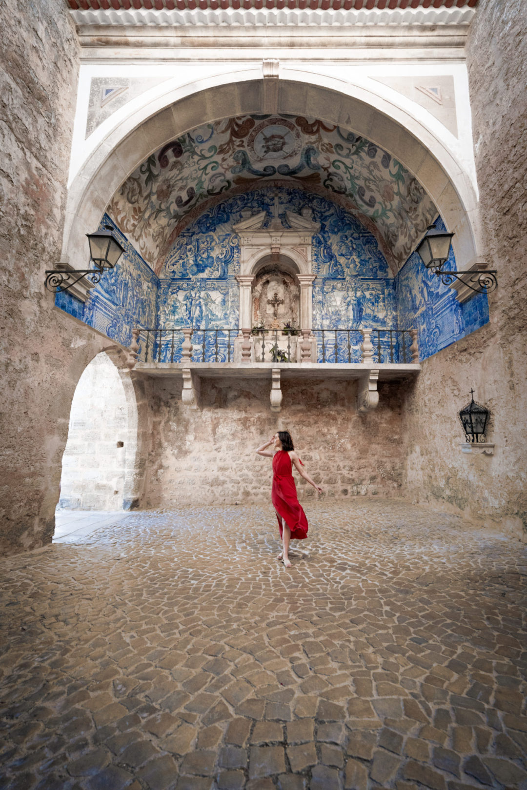 Travel Blogger Jordan Gassner wearing a red dress in an empty Porta da Vila in Lisbon, Portugal