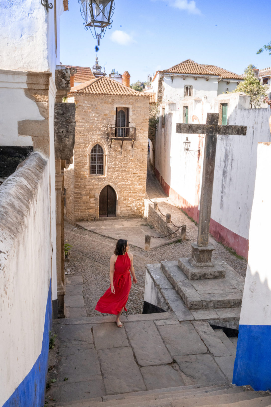 Travel Blogger Jordan Gassner walking up a set of stairs in the town of Obidos, Portugal outside of Torre De Maneys