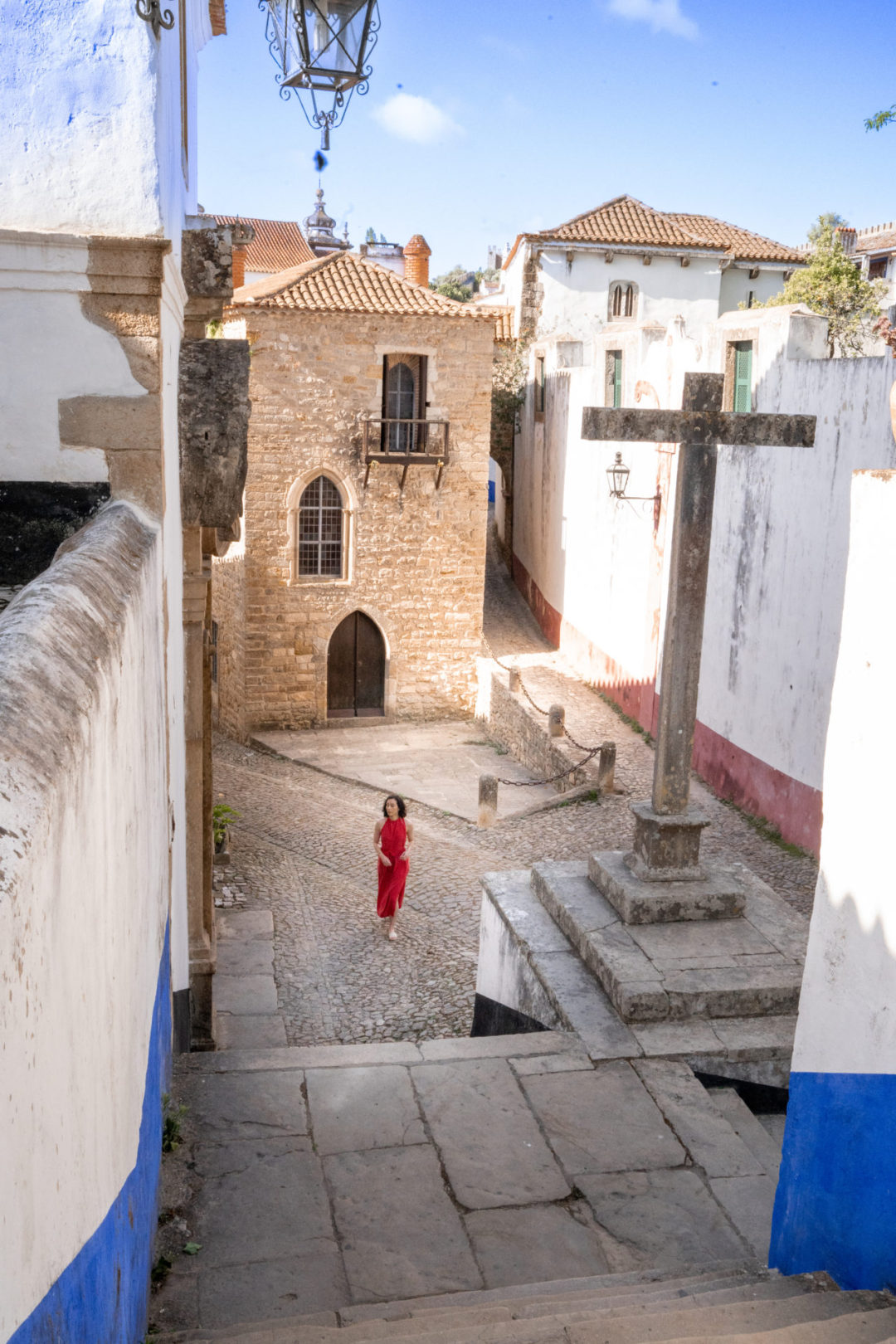 Travel Blogger Jordan Gassner walking along a cobblestone street in front of Torre De Maneys in Obidos, Portugal